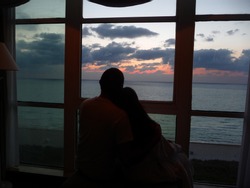 Couple watching the sunrise through a window overlooking the Atlantic Ocean in Miami Beach, Florida, spring 2011