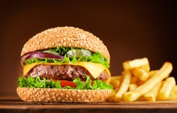 fresh cheeseburger with french fries on wooden table