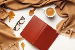 Autumn composition. Open inverted book glasses cashmere scarf, coffee cup with autumn leaves on a white background. Flat lay top view