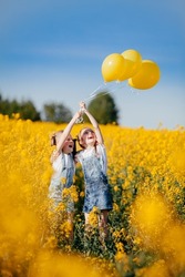 Happy emotions of children who are playing with balls on a yellow field of flowering rapeseed.