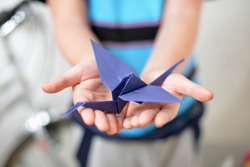 Origami crane in children's hands (soft focused)