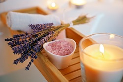Spiritual aura cleansing ritual bath for full moon ritual. Candles, aroma salt and lavender on tub table, close up