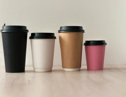 Color disposable paper cups with lids on wooden table