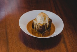 Sticky Toffee Pudding with Vanilla Ice Cream and Toffee Sauce, on a Wooden Table