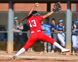 Girl winding up and throwing a fastball for a strike during a softball game