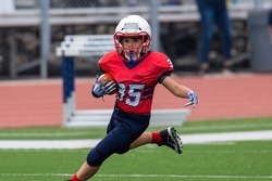 Young athletic boy playing in a youth tackle football game