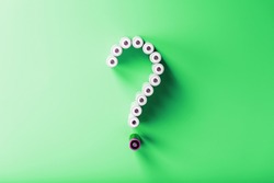 AA batteries in the form of a question mark on a green background with free space. The concept of environmental protection and renewable energy sources