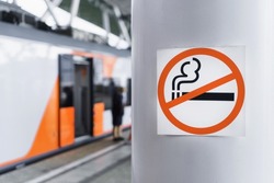 A sign prohibiting smoking on a pole near the railway platform. Smoking in public places is prohibited