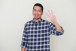 Adult Asian man smiling happy while showing three fingers sign
