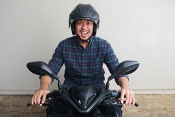 Adult Asian man showing excited expression when riding a motorcycle