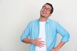 Adult Asian man touching his belly with relieved expression