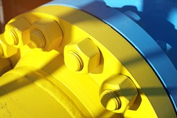 Two blue and yellow gas pipes are connected by large bolts and nuts. Background for suppliers of gas products and pipes. Close-up