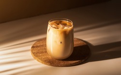 Glass of a iced coffee with cream milk. Cold brew coffee drink with ice. Early morning sun light. 