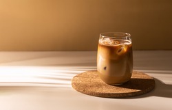 Glass of a iced coffee with cream milk. Cold brew coffee drink with ice. Early morning sun light. Copy space.