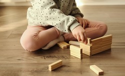 Little child plays a board game, kid builds from wooden bricks blocks. Children's educational games concept. 