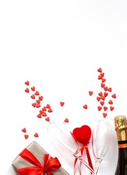 Valentine's Day background. Gift box, red hearts, two champagne glasses, bottle champagne on white background.Concept: Valentines day, wedding, birthday.Flat lay, copy space, vertical.