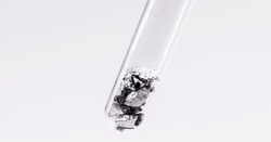 Chromium fragments inside test tube, industrial use ore, metallic chemical element, isolated on white background