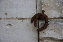 Horse shoes: two old horse shoes hang upside down on a French shutter retaining catch