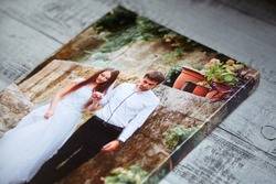 Canvas print. Photo printed on canvas. Sample of stretched wedding photography with gallery wrap, side view, closeup. Portrait on grey wooden surface
