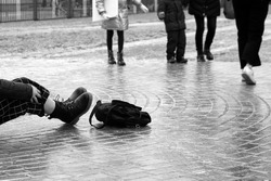 Ice crusted ground, paving slabs surface covered ice, slippery street, winter weather. Slipped girl lying on the sidewalk