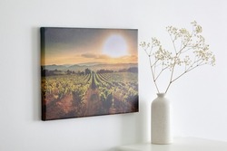 Canvas photo print with gallery wrap and flowers in vase, interior decor. Landscape photography hanging on white wall. picture with vineyard