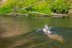 A man swims in a wild river with the current. Adventure traveling lifestyle. Concept wanderlust. Active weekend vacations wild nature outdoor. Summer rest.