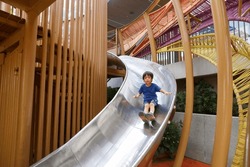 happy asian boy on playground. Kid slide down on slider at plublic playground.