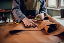 An experienced tanner at his master class shows how to work with leather, lays it out on the table.
