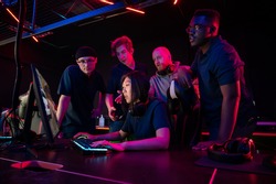 Asian girl playing in a computer club, guys standing behind and prompting