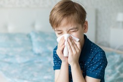 Caucasian boy suffers from a runny nose and allergic reactions to pollen. Colds viral diseases in children. Child at home
