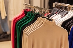 Outerwear for men and women. high-collar sweaters hanging on hangers in the store. Sale season