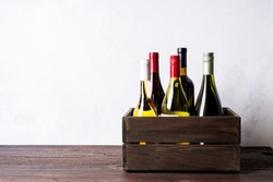 Set of different kinds bottles of champagne, white, red wine in wooden box on light background