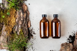 Two brown glass Mock up bottles of shampoo and conditioner of body care cosmetics over Natural background of real tree bark, tiny mosses and grass organic for cosmetic products with copy space. 