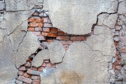 Large crack on the wall of an old brick house, crumbling plaster and broken, cracked bricks. Background image