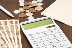 Calculator, passbook and Japanese money. In the passbook, it is written in Japanese as 