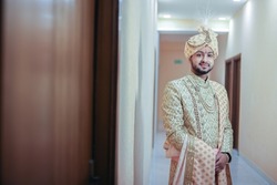 A groom posing for his wedding photo in a big fat Indian wedding celebrated in New Delhi, India. Indian groom dressed in Ivory Sherwani. Traditional Jain Wedding and Hindu. Indian wedding attire. Cute
