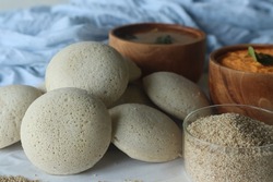 Steamed Little millet cakes or little millet idli. Made with a fermented batter of little millet, lentils. Served with coconut chutney. Shot with little millet in a wooden bowl