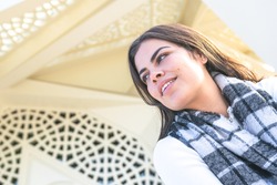 Portraiture of femaleYoung person with scarf is sitting on the stairs by interesting architecture modern marmara university mosque. Tourist attraction in Turkey.
