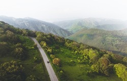 Aerial birds eye view of car on asphalt road in scenic caucasian mountains. Travel in Georgia