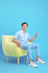 Asian handsome and cheerful young man using smart phone, sit on sofa, isolated on background
