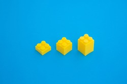 yellow cubic plastic block on blue paper background . stairs three step for growing and succeeding business isometric concept .