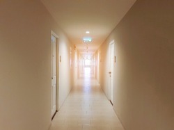 Long corridor in luxury condominium.The hallway is clean and luxurious.The corridor inside the apartment building has signs and fire escape doors in the building.