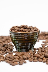 Fragrant roasted coffee beans on white background and small cup, energy drink.
