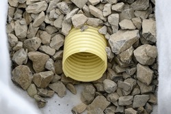 Yellow corrugated pipe with perforation in a trench with crushed stone and geotextile. Drainage works for the removal of ground water in the field.