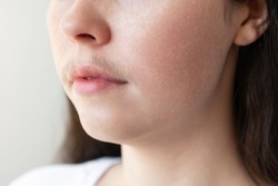 A close-up of a woman's face with a mustache over her upper lip. The concept of hair removal and epilation.