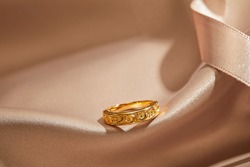 A gold ring on silk background with ribbon.gold wedding fashion jewelry for her