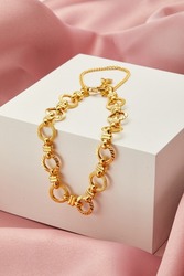 gold bracelet with white box on the pink silk background display