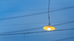 Classic style lighting lamp is glowing on blue sky and cable lines of the city as background. Electrical equipment for decoration object photo.