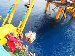 ROV crew deploys inspection class ROV into the sea next to wellhead platform.