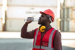 African american man worker drinking water and resting after working at container yard.